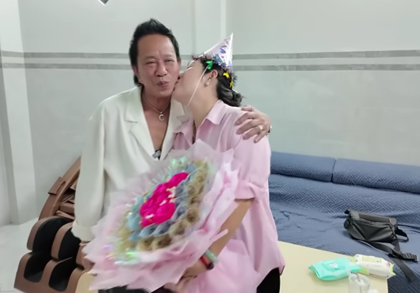 An image of Bảo Chung kneeling and presenting flowers to his wife