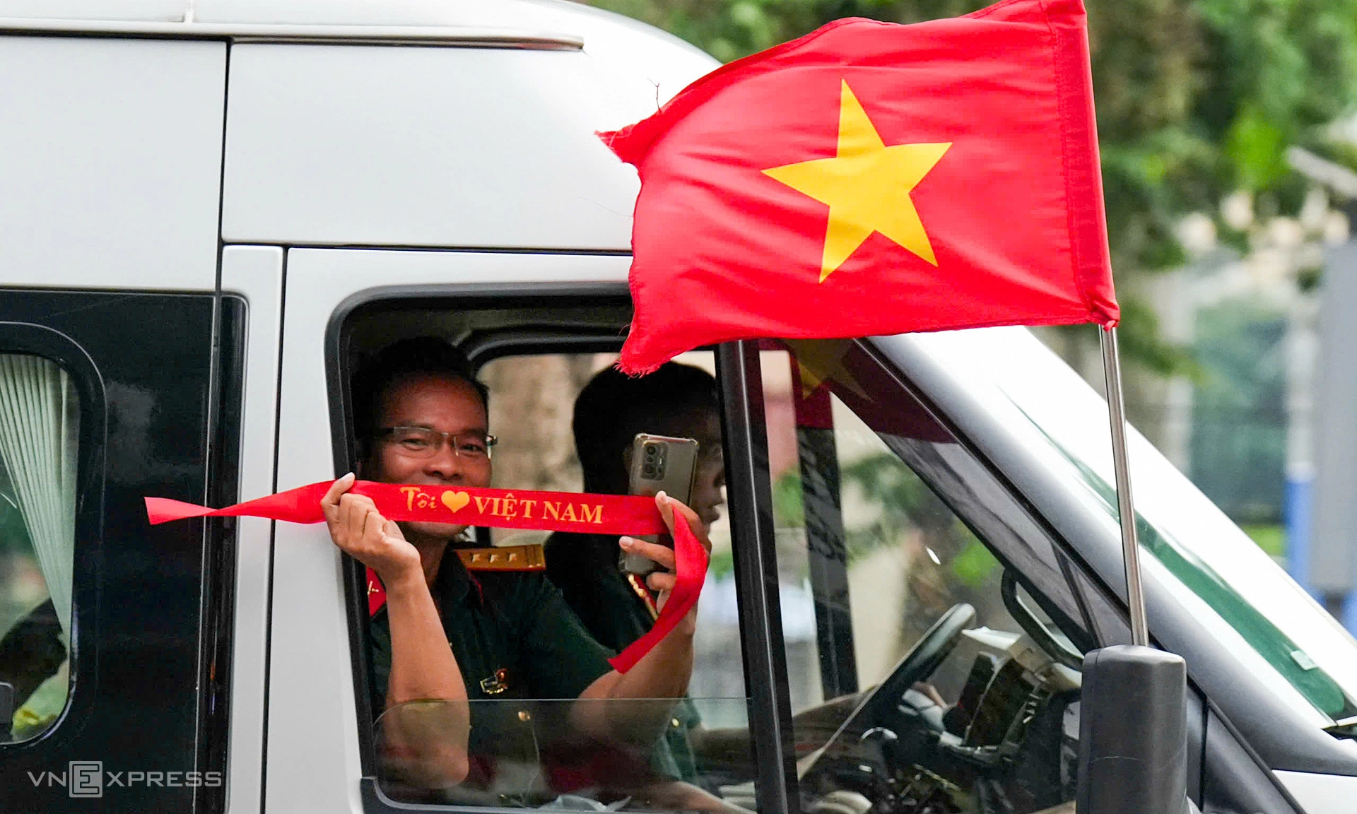 Thượng tá Nguyễn Thành Luân, giáo viên phụ trách khối Chiến sĩ Phòng hóa, mang theo băng-đô cờ đỏ sao vàng tặng người dân dọc tuyến diễu binh. Ảnh: Tùng Đinh