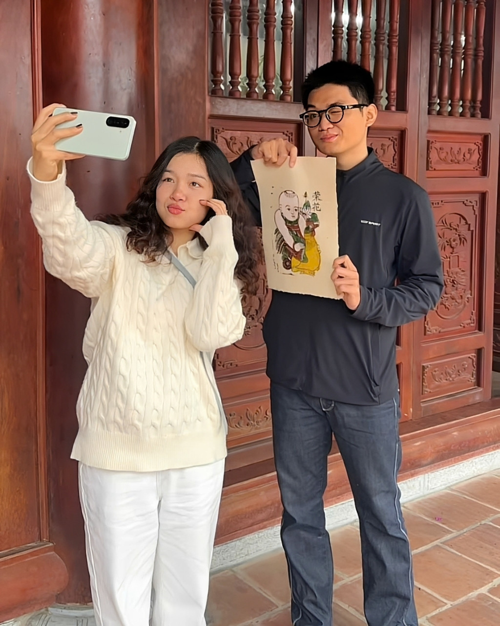 Nhung (áo trắng) cùng một người bạn chụp hình với bức tranh tự tay thực hiện