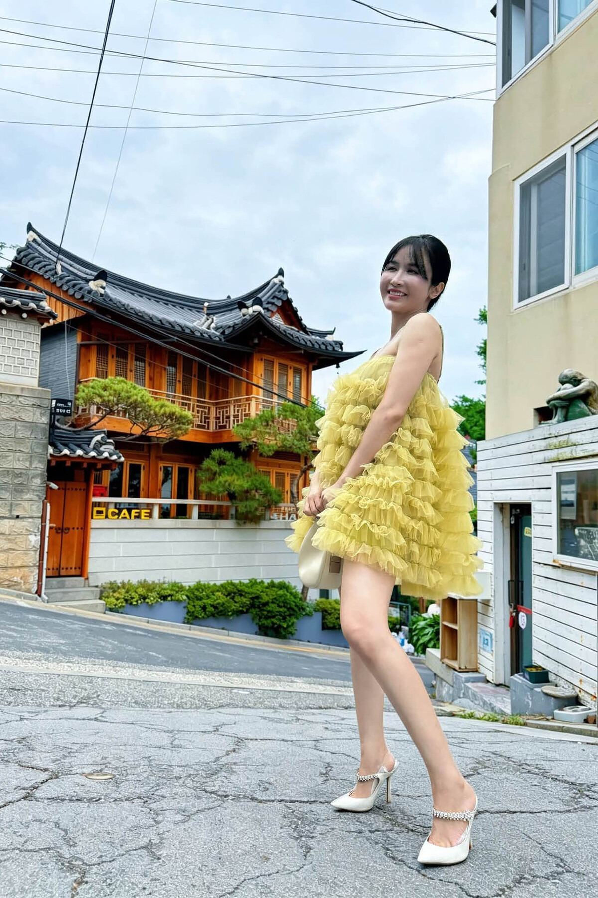Dạo chơi trên đường phố Hàn Quốc, Mina Phạm chọn mẫu váy ngắn vải tulle nhí nhảnh và làm điệu bằng đôi mules đính đá.