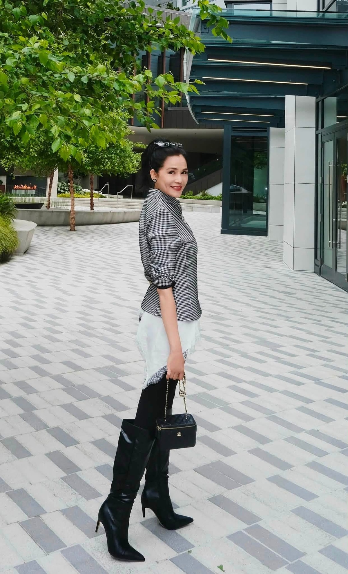 Ở một khung cảnh khác, Dạ Thảo diện áo hai dây lụa phối ren trắng, khoác sơ mi kẻ sọc, kết hợp quần skinny jeans đen và boots cao cổ dạo phố. Ảnh: Facebook Dạ Thảo