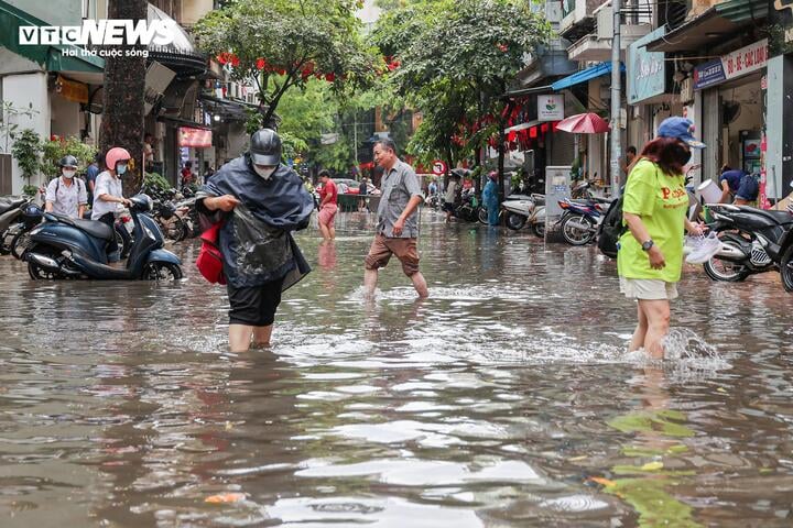 Người dân chật vật đi lại qua khu vực dềnh nước trên phố Hòe Nhai.