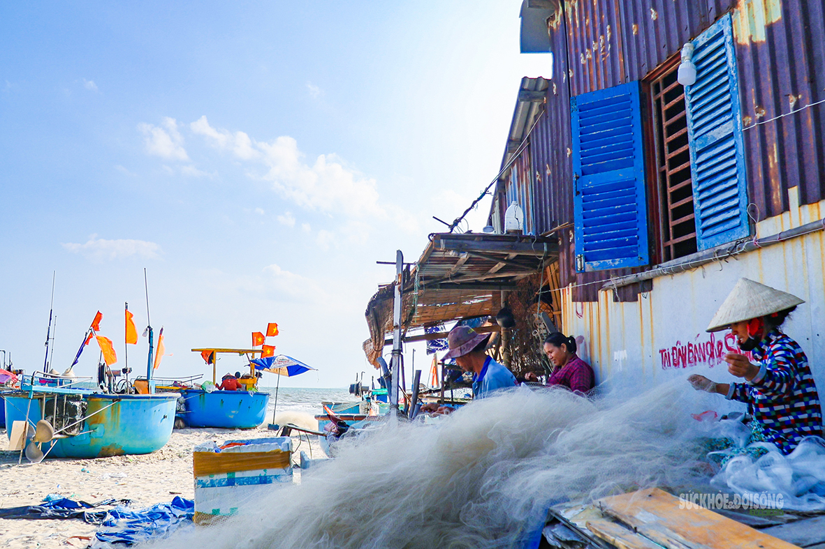 Người dân ngồi vá lưới bên những căn nhà sát mép biển. Ảnh: Lâm Nguyễn