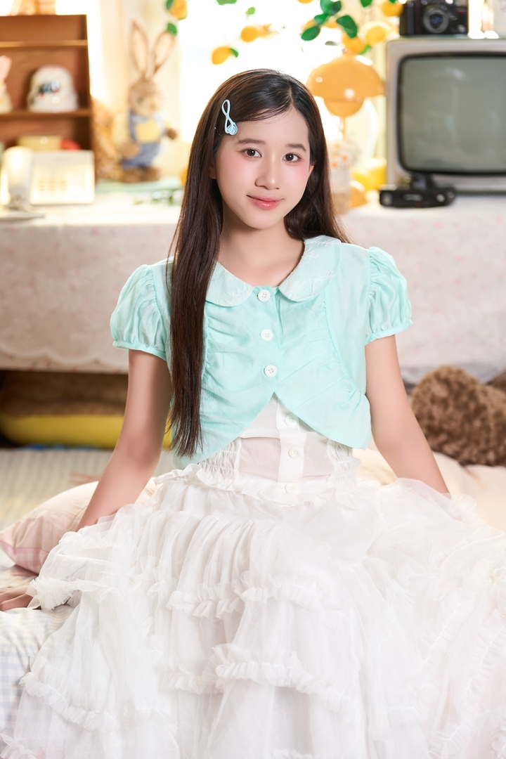 Ở đời thường, cô diện váy trắng kết hợp áo khoác xanh pastel, cài tóc nhỏ xinh, mang đến hình ảnh ngọt ngào, hồn nhiên.
