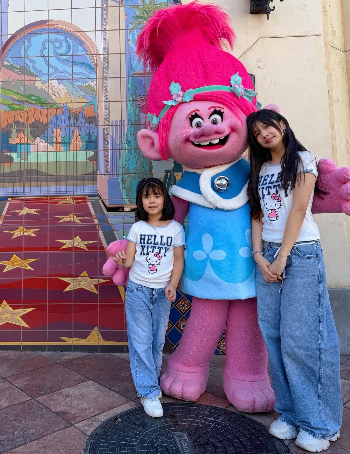 Hai chị em Na và Nấm mặc đồ đôi với áo phông Hello Kitty, quần jeans và sneakers.