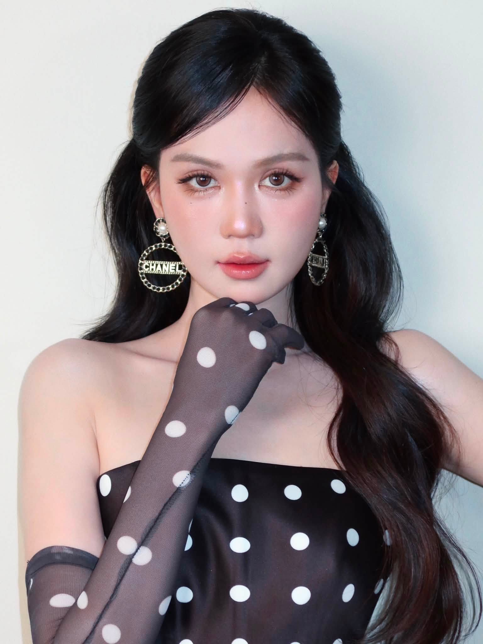 Họa tiết chấm bi trắng trên nền đen mang hơi hướng retro, trong khi phom váy ngắn và đường cắt hiện đại khiến tổng thể trở nên trẻ trung hơn. Đôi găng tay xuyên thấu đồng họa tiết kéo dài gần hết cánh tay cũng là chi tiết đáng chú ý, giúp một chiếc váy chấm bi quen thuộc có thêm nét cá tính.