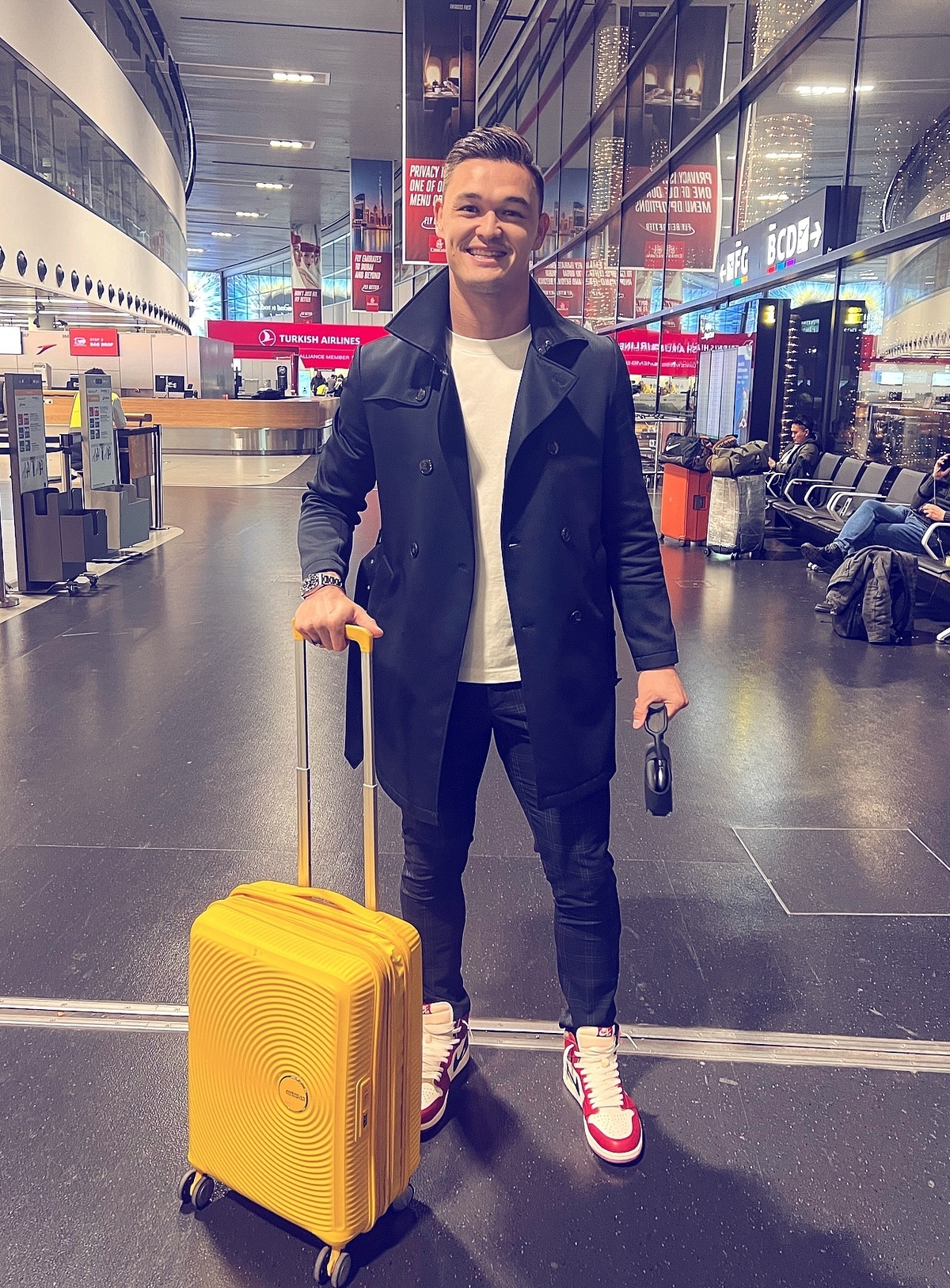 Thời trang sân bay của Patrik với trench coat dáng ngắn, quần skinny jeans và sneakers.