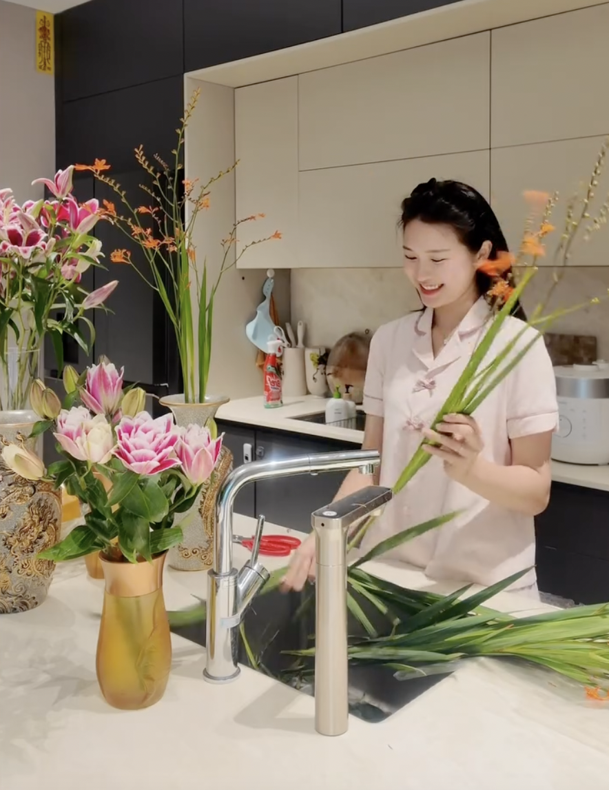 Không gian phía sau Hải My cũng nhanh chóng thu hút sự chú ý. Căn bếp được thiết kế hiện đại, tông màu sáng, gọn gàng và sang trọng. Trên bàn là những cành hoa và đồ dùng phục vụ việc trang trí, cho thấy nàng WAG đang tự tay chuẩn bị tổ ấm cho dịp Rằm tháng 7.