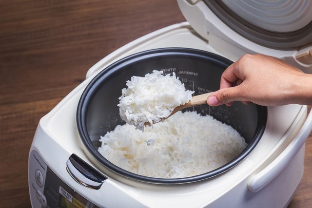 Dùng đũa hoặc muôi xới nhẹ từ dưới lên để hơi nước phân bố đều, giúp cơm tơi và không bị dồn thành từng mảng.