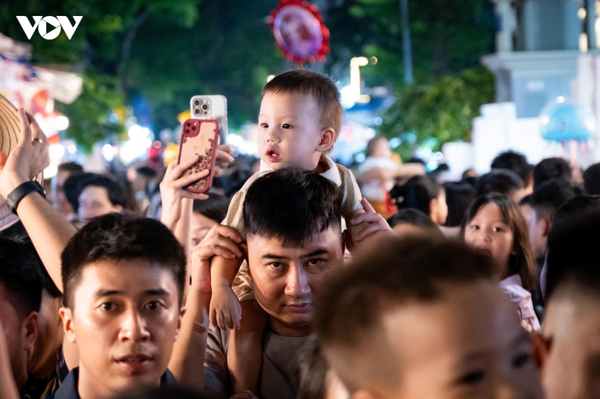 Một số phụ huynh cho trẻ nhỏ ngồi trên vai để vừa dễ di chuyển, vừa giúp các em có thể quan sát những món đồ chơi rực rỡ hai bên đường.