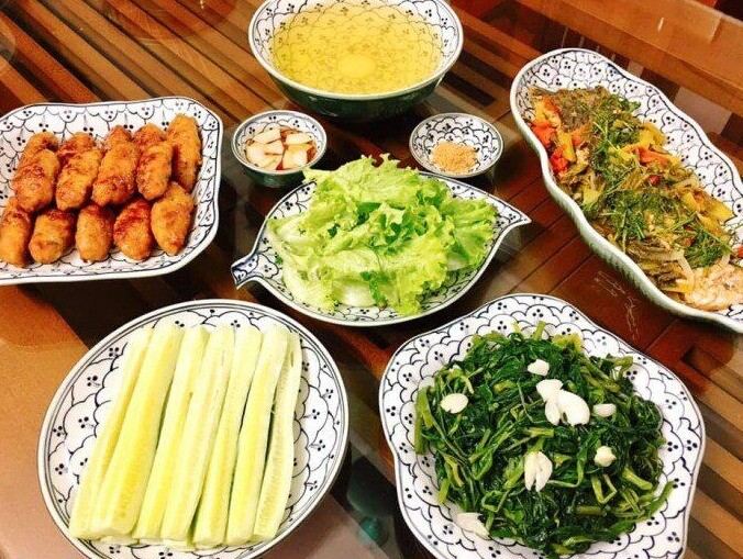 Mâm cơm này gồm các món: Cá chép om dưa, rau muống xào tỏi, nem lụi (Ảnh: Thu Hằng)