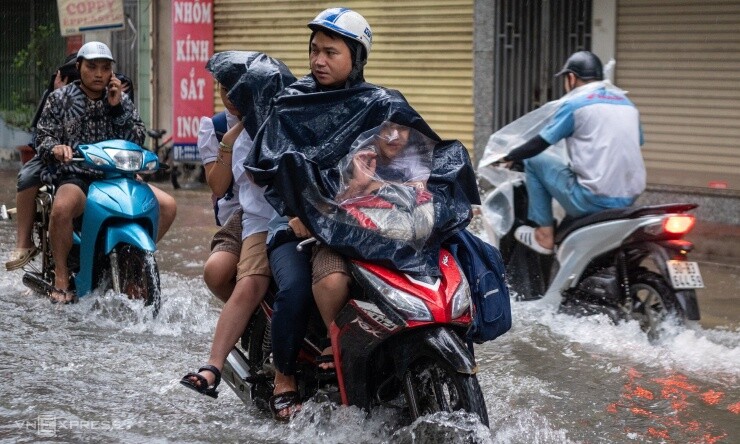 Một phụ huynh đèo ba cháu nhỏ đến trường, sáng 17/9. Ảnh: Thế Bằng