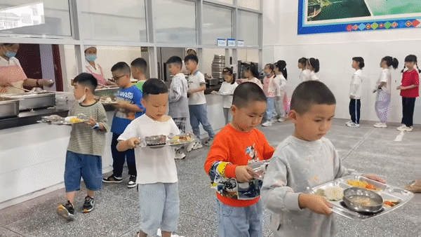 Một hàng dài các em học sinh sẽ xếp hàng và lần lượt nhận thức ăn.
