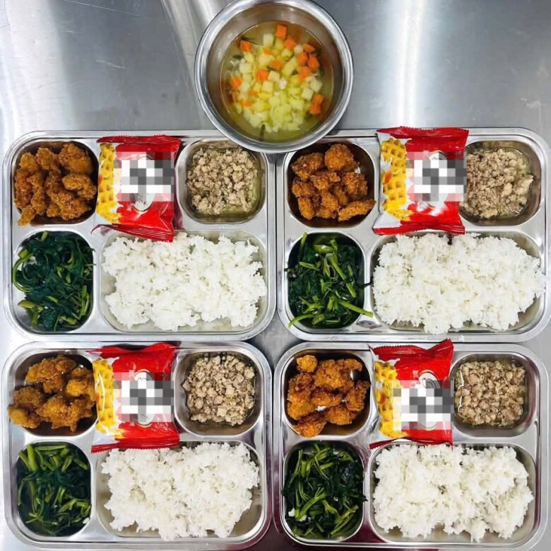 Suất ăn đầy đặn với thịt chiên xù, thịt băm, rau xào, canh và cơm.