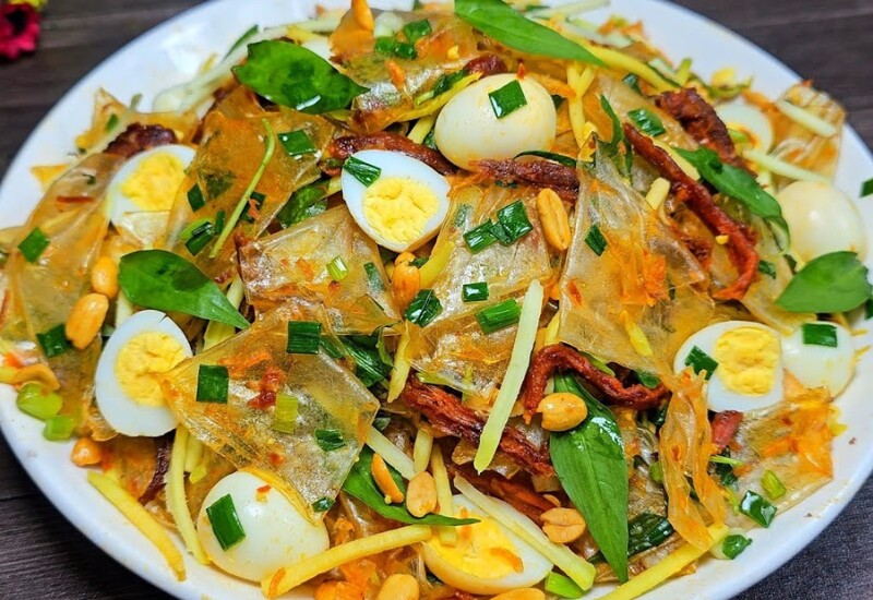 Bánh tráng trộn là món ăn vặt đường phố quen thuộc ở Việt Nam. Món ăn này hấp dẫn bởi vị chua, cay, mặn, ngọt hòa quyện. Bánh tráng dai mềm trộn cùng xoài xanh, rau răm, đậu phộng, khô bò và nước sốt tạo nên hương vị càng ăn càng cuốn.