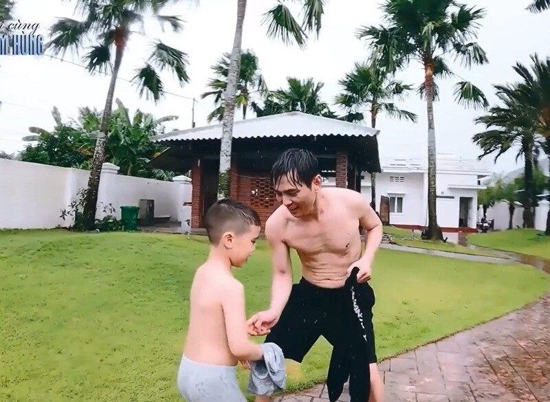 Hai bố con Lâm Hùng vui vẻ chạy nhảy, đùa giỡn cùng nhau dưới làn mưa, tận hưởng trọn vẹn không khí yên bình của quê nhà.