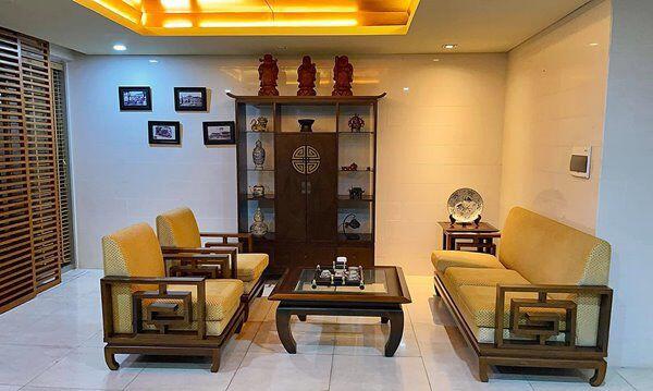 Một góc không gian phòng trà mang phong cách Á Đông truyền thống đầm ấm. Bộ bàn ghế gỗ tự nhiên chạm khắc tinh xảo kết hợp cùng tủ trang trí trưng bày bình gốm cổ và tượng phong thủy may mắn.
