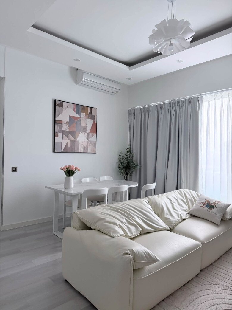 Bộ sofa bọc da tone màu kem mềm mại là điểm nhấn êm ái cho không gian sinh hoạt chung. Góc bàn ăn đặt cạnh bức tranh nghệ thuật hiện đại tạo cảm giác ấm cúng cho các bữa ăn gia đình.