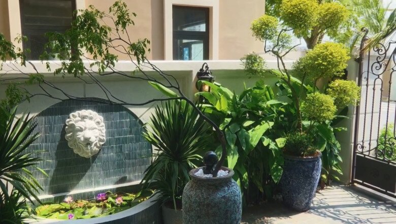 Toàn cảnh góc tiểu cảnh đài phun nước kết hợp cùng hệ thống cây cảnh đa dạng từ dáng bonsai đến cây lá rộng. Chiếc bình gốm xám đốm xanh và chum đá trang trí được sắp đặt khéo léo, mang đến không gian thư giãn đậm chất thiên nhiên.