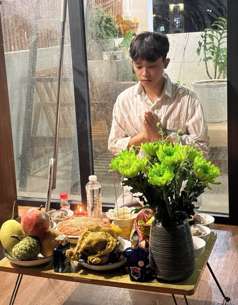 Khoảnh khắc Hồ Văn Cường chắp tay thành kính cầu nguyện trước mâm cúng. Không gian cúng lễ hướng ra khoảng ban công kính thoáng đãng, hé lộ phần nào góc sống bình yên và hiện đại của căn nhà.