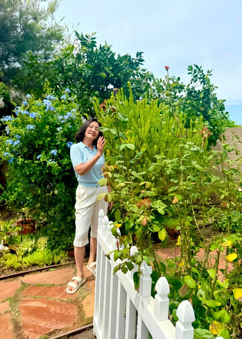 Góc sân nhỏ được bao bọc bởi hàng rào gỗ trắng tinh khôi, nổi bật trên nền đá lát tự nhiên và những bụi hoa thanh liễu, hoa hồng đua nhau khoe sắc. Hồng Đào tự tay chăm sóc từng gốc cây, tạo nên không gian sống rạng rỡ và tràn đầy năng lượng tích cực.