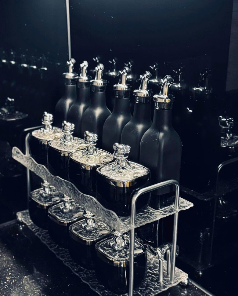 Sự chỉn chu của gia chủ được thể hiện qua những khay đựng và chai lọ tối giản được sắp xếp ngăn nắp trên kệ. Từng chi tiết nhỏ đều đồng bộ hoàn hảo với ngôn ngữ thiết kế huyền bí của cả căn hộ.