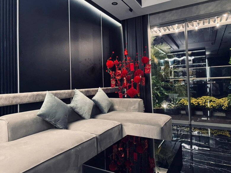 Chiếc sofa màu xám ghi êm ái chiếm trọn vị trí trung tâm của phòng sinh hoạt chung. Cạnh đó, khung cửa kính kịch trần mở ra tầm nhìn thoáng đãng, kết nối hài hòa giữa phòng khách và khoảng ban công ngập tràn cây xanh.