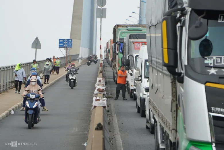 Ôtô nối thành hàng dài, san sát trên cầu Phú Mỹ, nhiều thời điểm gần như không thể di chuyển. CSGT phải điều tiết từ xa, hạn chế phương tiện từ phía quận 7 cũ dồn vào khu vực ùn tắc. Theo ghi nhận, lượng xe container ra vào cảng tăng cao, cùng dòng phương tiện đổ về cao tốc TP HCM - Long Thành - Dầu Giây khiến đường Võ Chí Công (Vành đai 2) quá tải. Trong khi đó, hướng ngược lại từ TP Thủ Đức cũ sang quận 7 cũ khá thông thoáng.