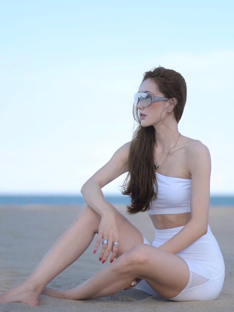 Paris Tiên khoe body săn chắc trong set đồ thể thao tông trắng đồng điệu, gồm áo croptop lệch vai kết hợp quần biker short cạp cao.