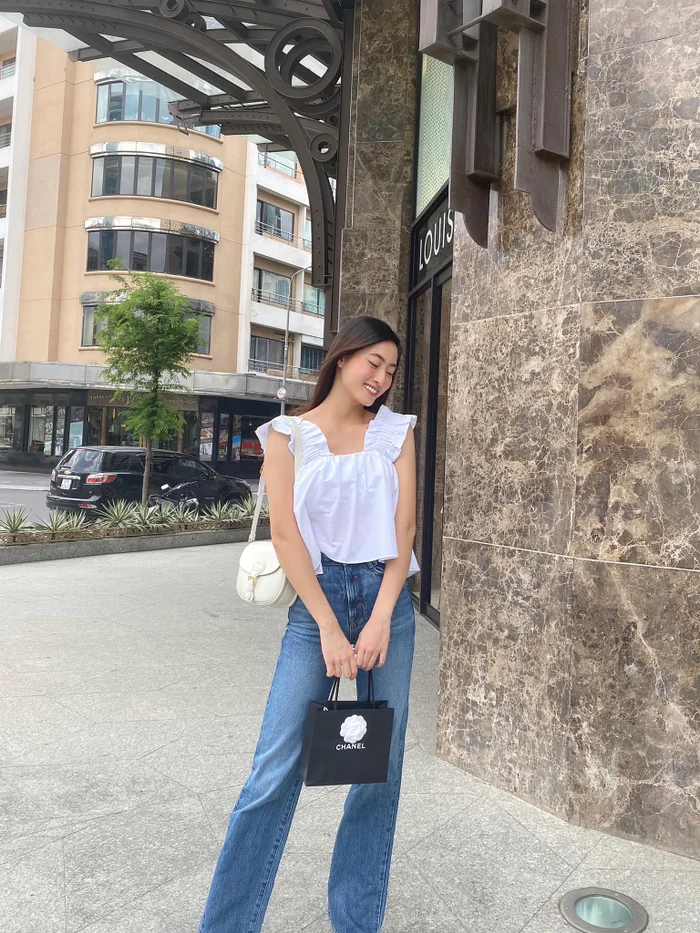 Lương Thùy Linh phối áo babydoll trắng cùng quần jeans cạp cao, tạo tổng thể trẻ trung và cân đối.