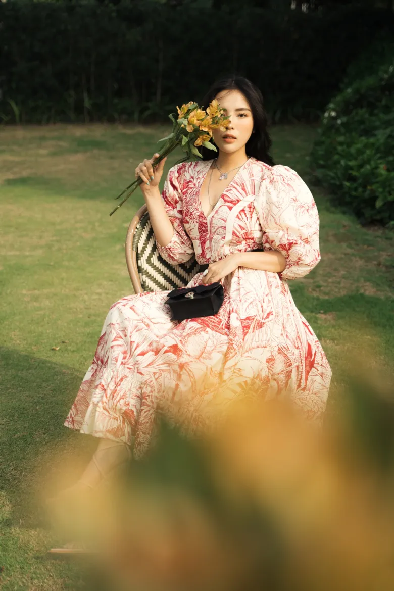 Trong khung hình, Hoa hậu Việt Nam 2014 kết hợp đầm với túi Christian Louboutin, sandals màu be cao gót cùng chuỗi dây chuyền mặt khóa.