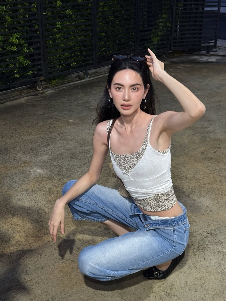 Ở một lần xuống phố khác, Mai Davika làm mới phong cách với áo hai dây trắng viền họa tiết da báo phối quần jeans ống rộng cạp thấp. Kính râm đen và khuyên tai vàng bản lớn hoàn thiện bản phối mang hơi hướng Y2K, trẻ trung và cá tính.