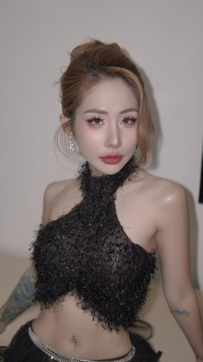 Trong một lần xuất hiện khác, nữ ca sĩ tiếp tục lựa chọn công thức áo dáng ngắn kết hợp chân váy mini cạp thấp. Chất liệu ánh kim giúp trang phục bắt sáng, trong khi phần chân váy gọn tạo cảm giác năng động. Cách phối này cũng gợi nhớ đến tinh thần thời trang Y2K vốn đề cao những phom dáng ngắn và cách kết hợp mang tính tương phản.