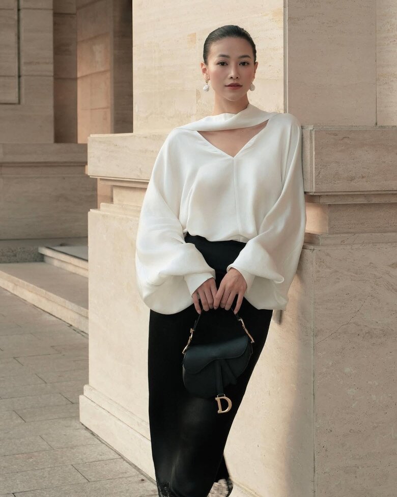Với Phương Khánh, bloues cách điệu và chân váy là công thức được biến hóa linh hoạt qua nhiều kiểu dáng và chất liệu. Ở set đồ này, cô chọn sơ mi trắng mix cùng chân váy đen tạo nên diện mạo vừa thanh lịch vừa hiện đại. 