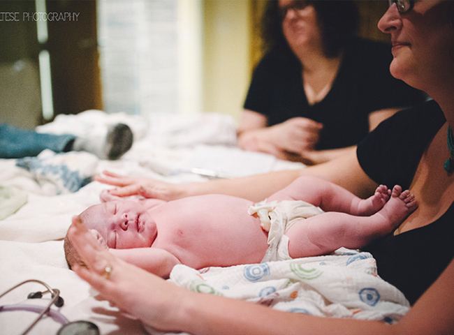 Em bé đang được bác sĩ vệ sinh sạch sẽ, đo cân nặng, chiều dài sau khi chào đời.
