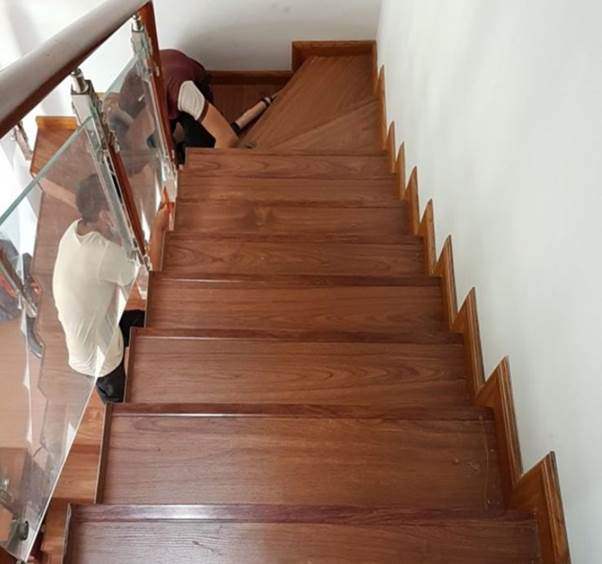 Mặt bậc cầu thang ốp gỗ công nghiệp màu cánh gián, lan can kính đơn giản