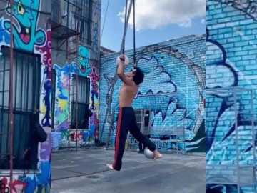 Chàng trai vừa quay bóng bằng miệng, vừa giữ thăng bằng trên dây