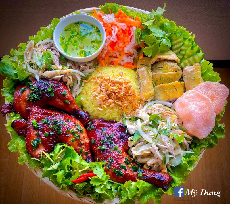 Xôi gà 3 món của Mỹ Dung gồm đùi gà nướng xá xíu - gỏi gà xé phay - gà luộc lá chanh cùng các món ăn kèm như gỏi, bánh phồng tôm và nước canh.
