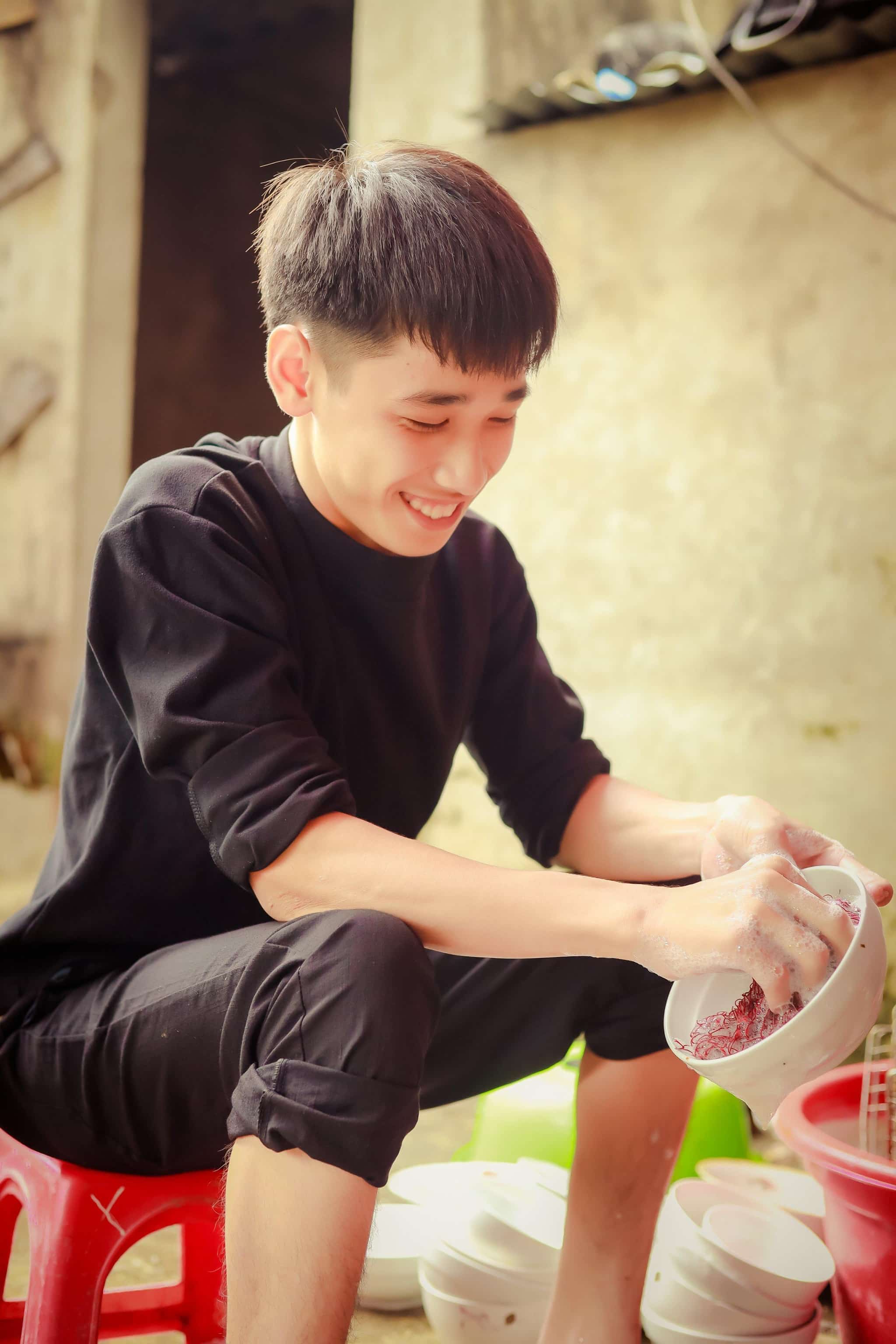 Em Hùng đang rửa chén tại quán ăn gần trường, em luôn nở nụ cười hiền lành dễ mến. Ảnh: Nguyễn Anh Tài