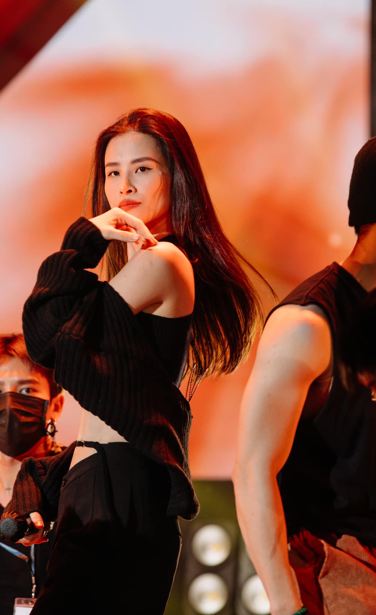 Nữ ca sĩ diện set đồ màu đen trendy với chiếc áo cắt xẻ trễ nải bắp tay thon gọn cùng hàng xương quai xanh quyến rũ. Tuy nhiên, sự chú ý lại dồn toàn tập vào vòng eo con kiến nhờ khoảng cắt xẻ nghệ thuật của chiếc quần ống rộng.