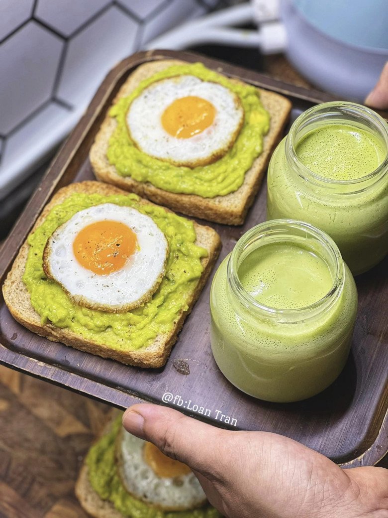 Bánh mỳ nguyên cám, topping bơ nghiḕn, trứng ṓp laThêm ly sữa hạt vị rau.