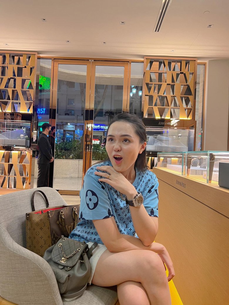 Áo phông cổ chui bình thường nhưng lại mang họa tiết monogram của nhà mốt Pháp, tay đeo đồng hồ Hublot, bên cạnh là túi tote book của Louis Vuitton và balo của Chanel.