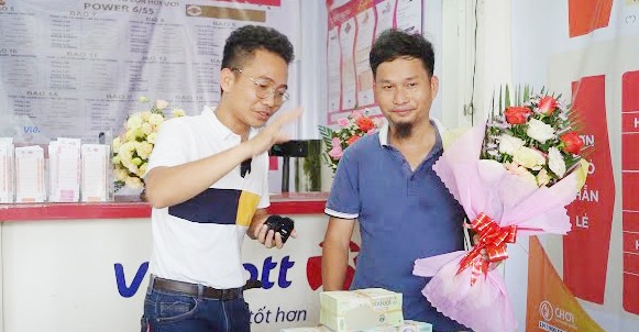 Anh Vương (áo xanh) nhận tiền mặt ngay tại đại lý vé số.