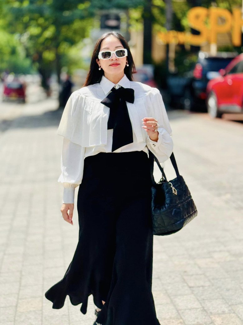 Combo thời trang có những điểm nhấn hút mắt là các chi tiết bèo nhún. Phần quần cạp cao màu đen hỗ trợ bà mẹ giấu dáng sau sinh.