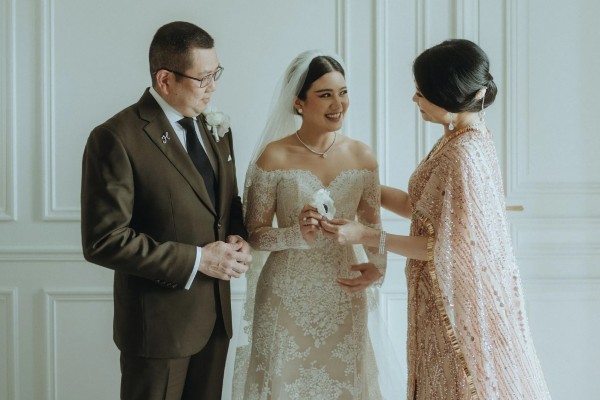 Valencia trong thiết kế váy cưới trễ vai, lúp đội đầu bằng ren rạng rỡ bên cạnh bố mẹ.