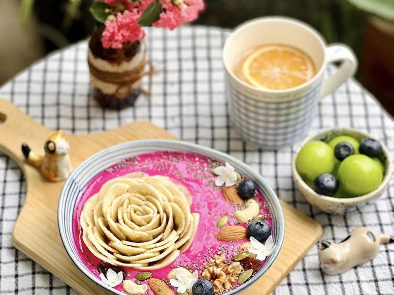 Smoothie chuối, thanh long đỏ, sữa chua Hy Lạp và các loại trái cây tươi, hạt dinh dưỡng được chị Trang trang trí bằng một bông hoa chuối. 
