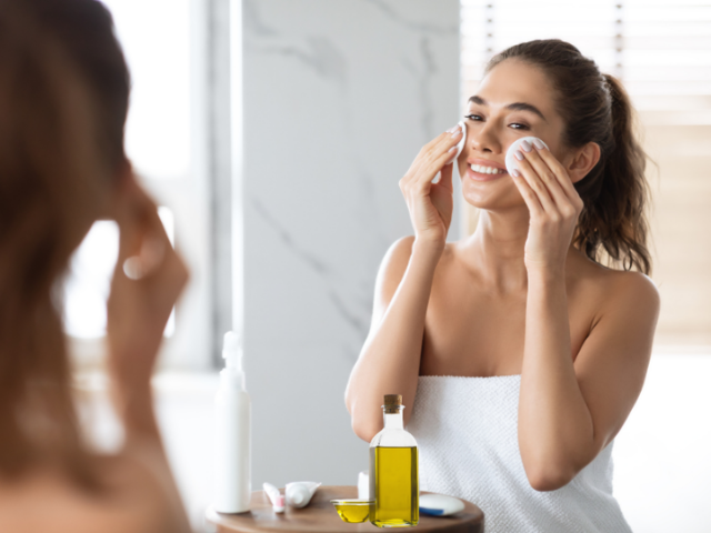 A woman applying olive oil to her face