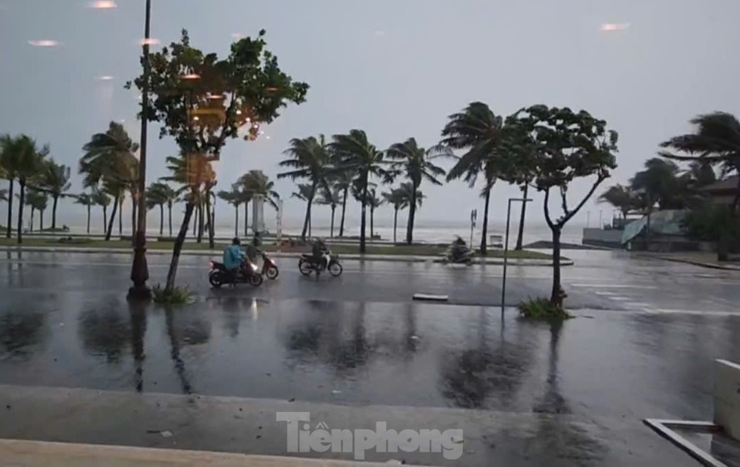 Người đi xe máy đứng lại trên đường biển vì gió quá mạnh không thể chạy tiếp.