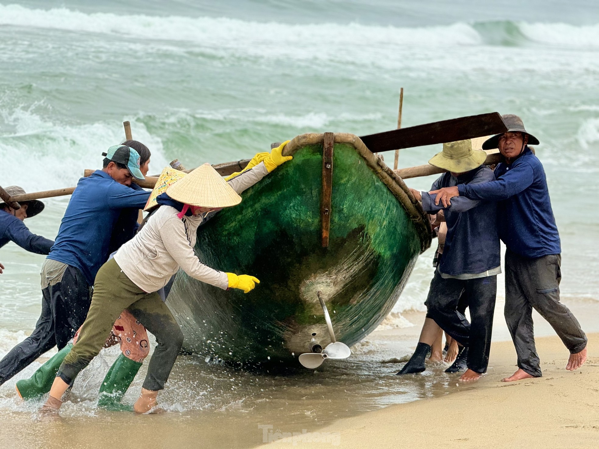 Ngay khi thuyền vừa cập bờ, những người vợ của ngư dân cũng khẩn trương ra hỗ trợ chồng con đưa chiếc thuyền vào sâu trong bờ để tránh những con sóng lớn.