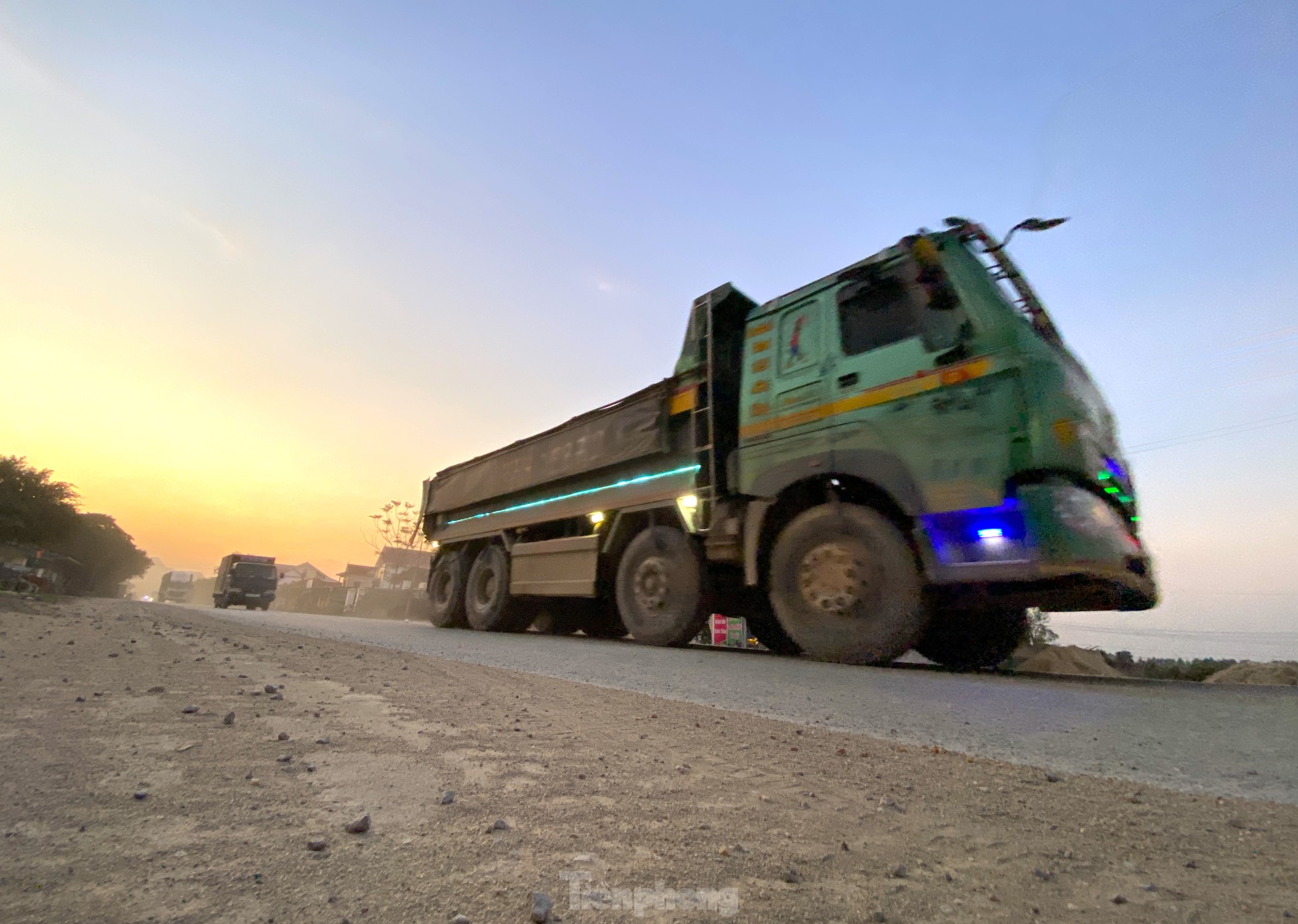 Cát, đá rơi vãi từ xe chở vật liệu phục vụ công trình và các dự án khác phủ kín mặt đường.